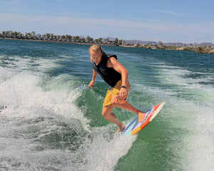 Wake Surfer riding the Ozark board wearing a Pit and Barrel life jacket competition vest in black
