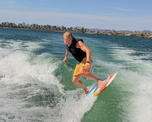 Wake Surfer riding the Ozark board wearing a Pit and Barrel life jacket competition vest in black