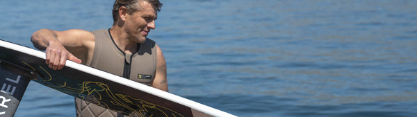 Man holding a foil wake surfboard with a blue water background