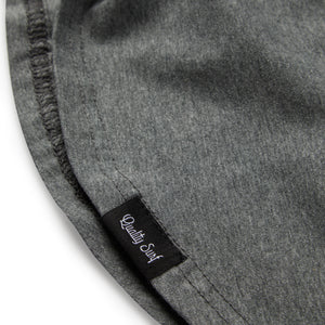 detail view of a 'quality surf' tag for a grey tee shirt showing scooped bottom. 