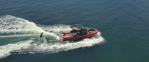Aerial view of a Super Air Nautique G23 boat while woman wake surfer rides a wave. Image shows Ozark 53