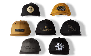 image of 7 hats logos up. all hats are from Pit and Barrel surf on white background with shadows. one says 'Lost on the Lake'.